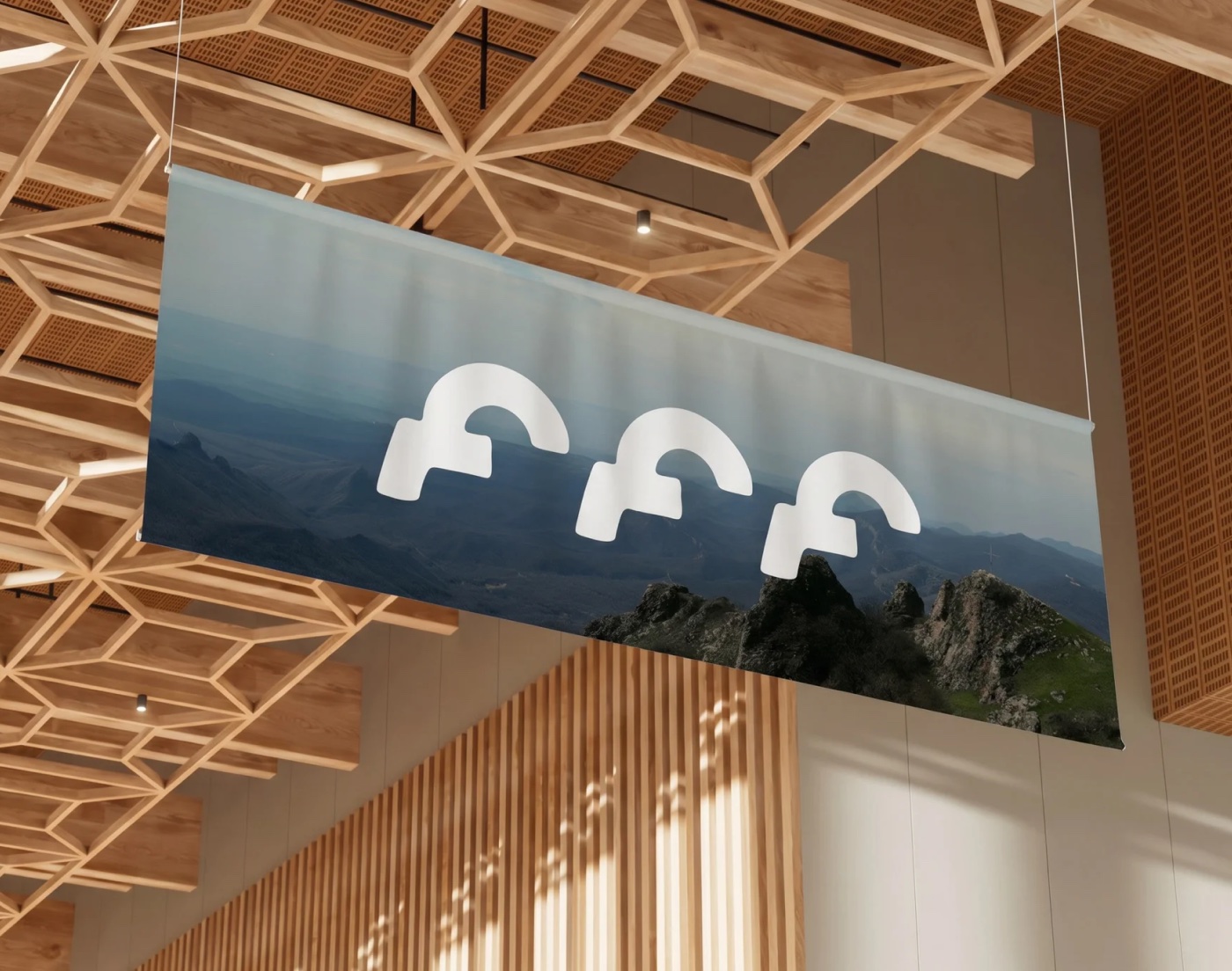 Hanging fabric banner with the event's logo lockup over a mountain photo, in a timber-lattice hall