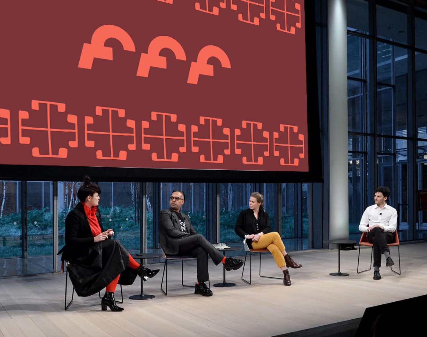 Panel discussion on a stage in front of a large red Georgian logo-pattern backdrop